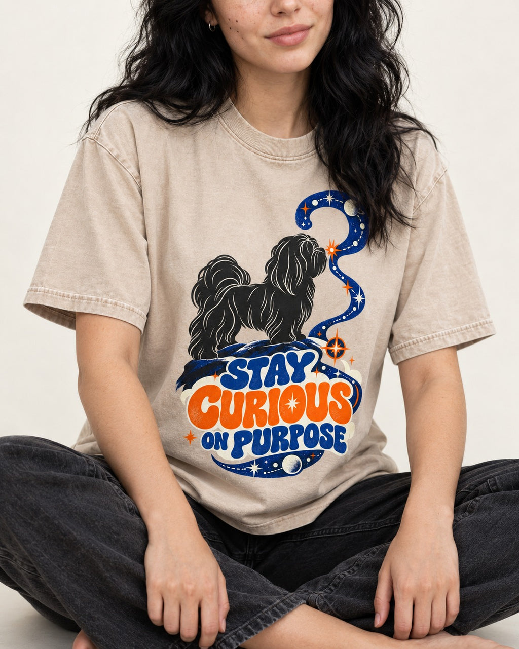 Stay Curious on Purpose Shih Tzu Washed Tee in Apricot, worn by a seated model