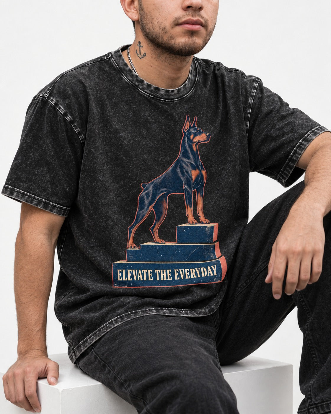 Doberman Elevate the Everyday Podium Graphic Washed Tee in Black, worn by a seated model