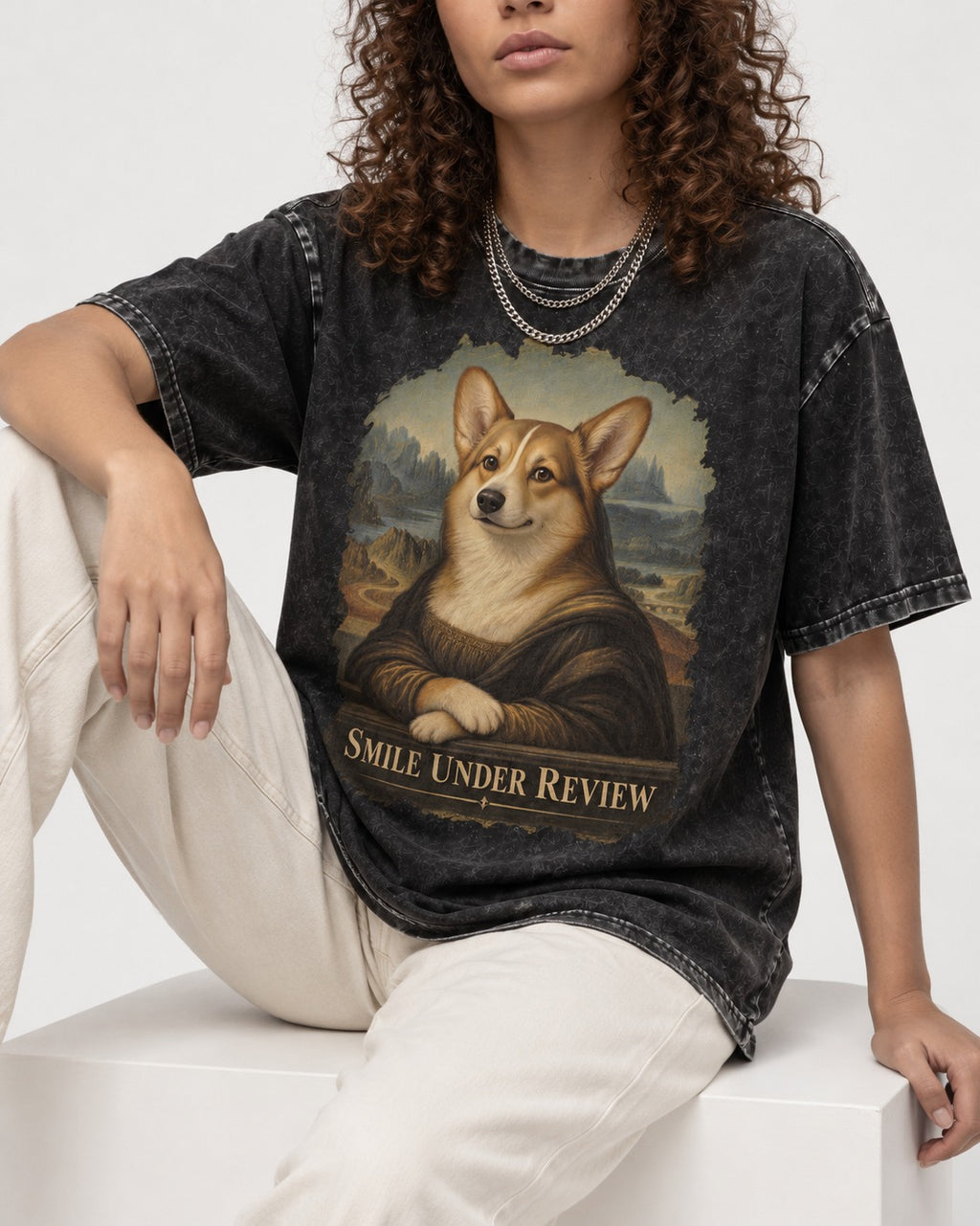 Corgi Smile Under Review Mona Lisa Portrait Washed Tee in Black, worn by a seated model
