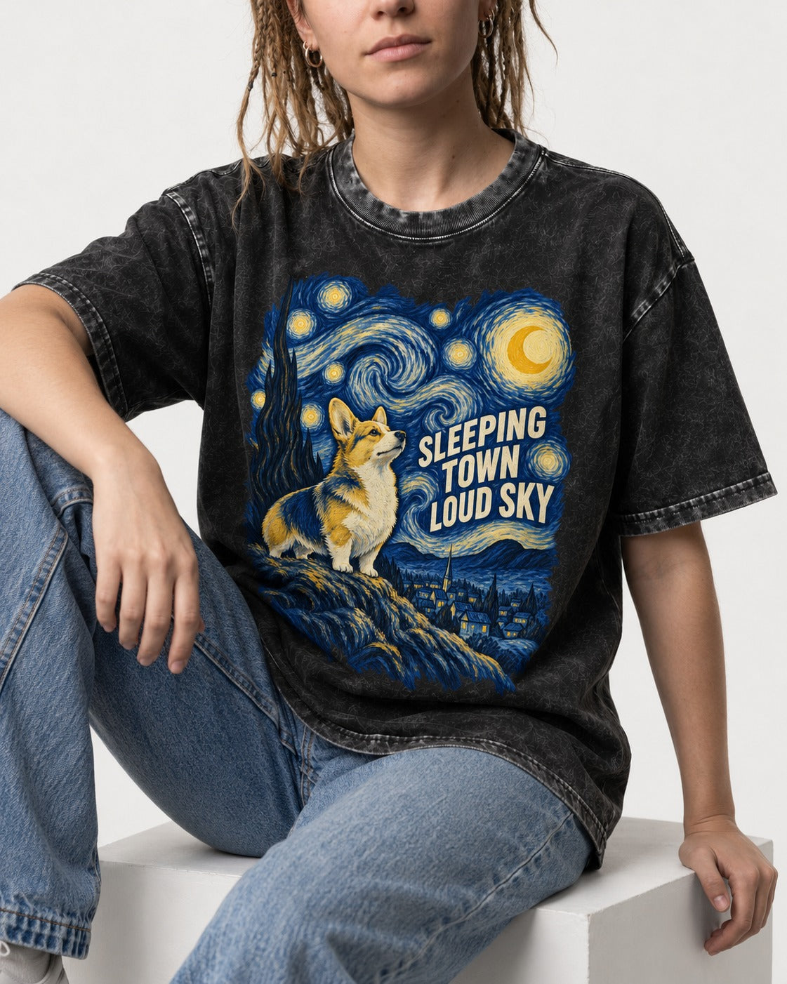 Corgi Sleeping Town Loud Sky Starry Night Washed Tee in Black, worn by a seated model