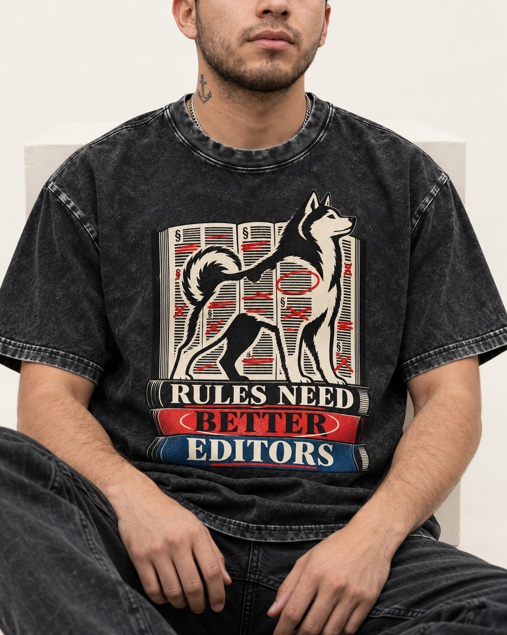 Husky Rules Need Better Editors Book Stack Graphic Washed Tee in Black, worn by a seated model