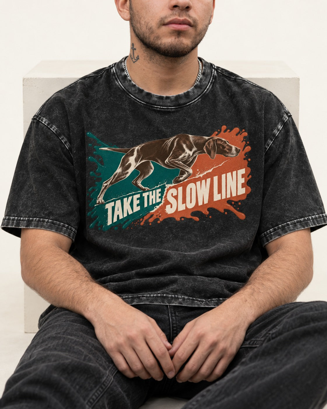 German Shorthaired Pointer Take The Slow Line Paint Splash Graphic Washed Tee in Black, worn by a seated model