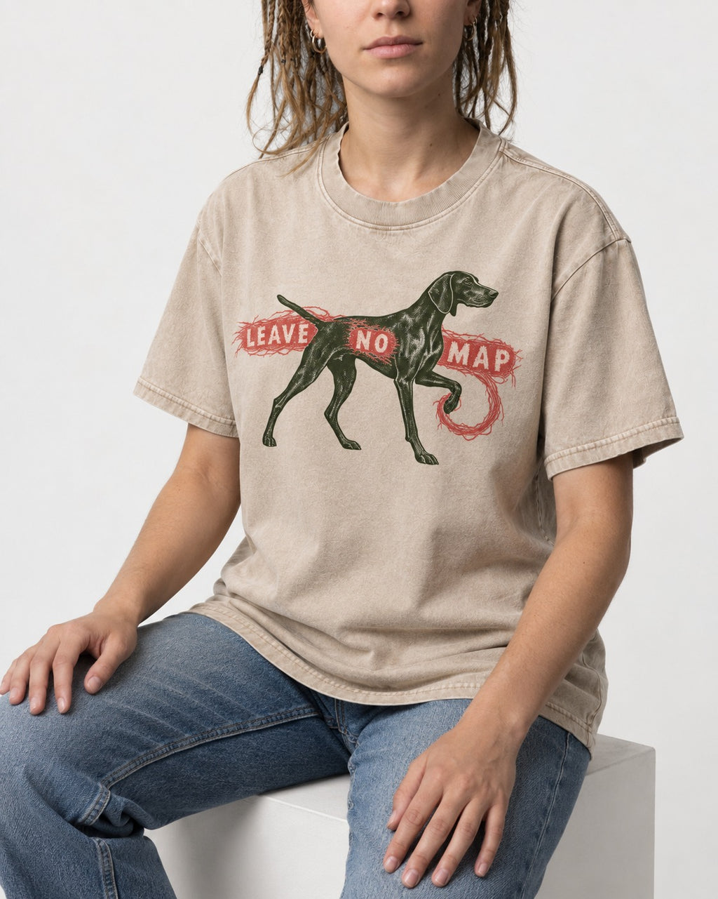Leave No Map German Shorthaired Pointer Washed Tee in Apricot, worn by a seated model