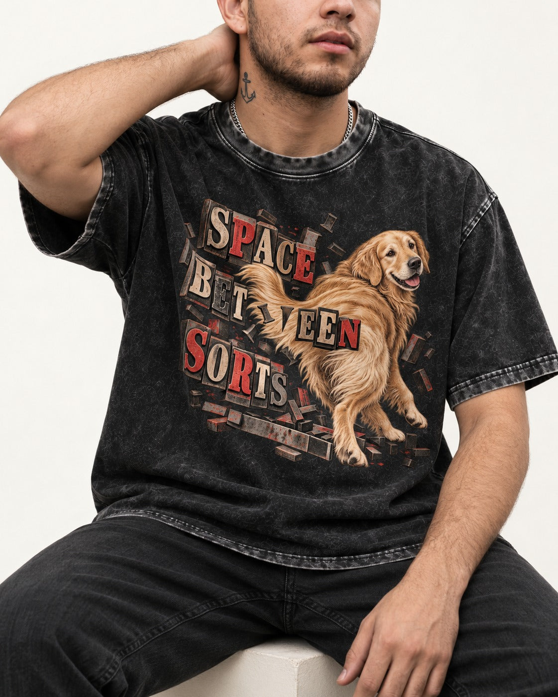 Golden Retriever Space Between Sorts Letterpress Graphic Washed Tee in Black, worn by a seated model