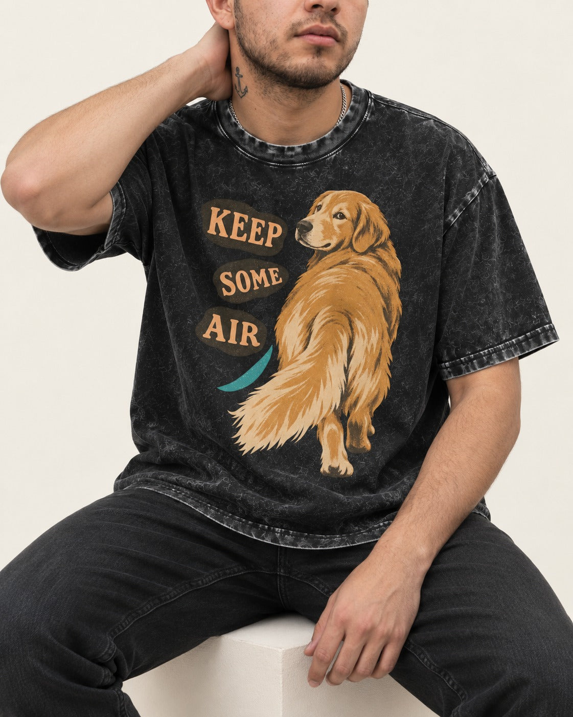 Golden Retriever Keep Some Air Looking Back Graphic Washed Tee in Black, worn by a seated model