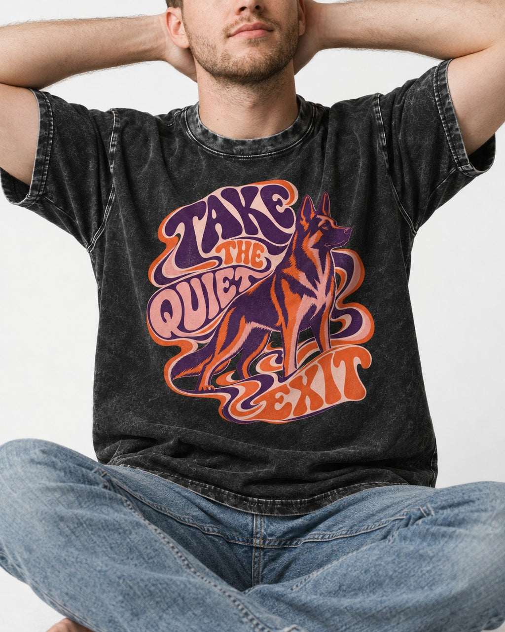 Take The Quiet Exit Psychedelic German Shepherd Dog Graphic Washed Tee in Black, worn by a seated model