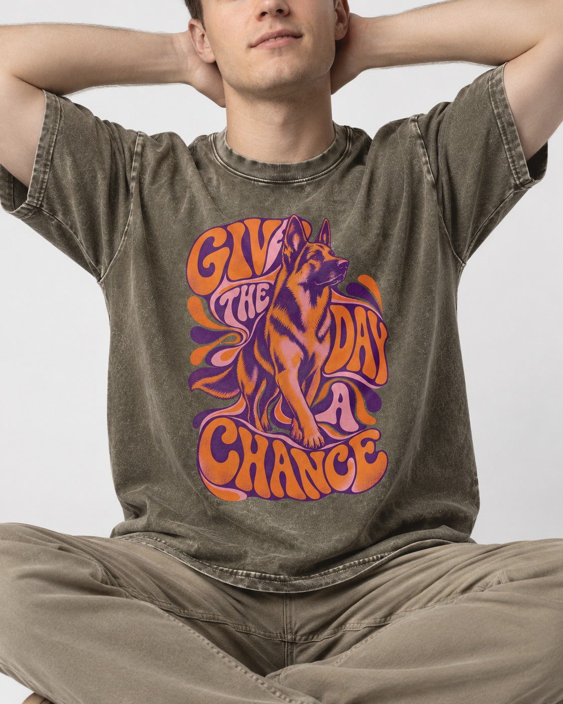Give The Day A Chance Psychedelic German Shepherd Dog Graphic Washed Tee in Army Green, worn by a seated model