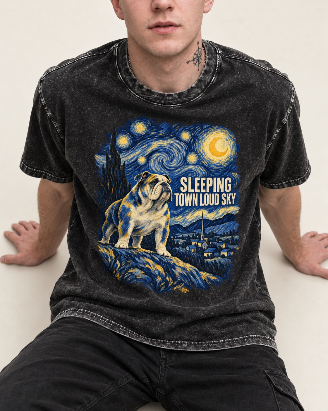 English Bulldog Sleeping Town Loud Sky Starry Night Graphic Washed Tee in Black, worn by a seated model