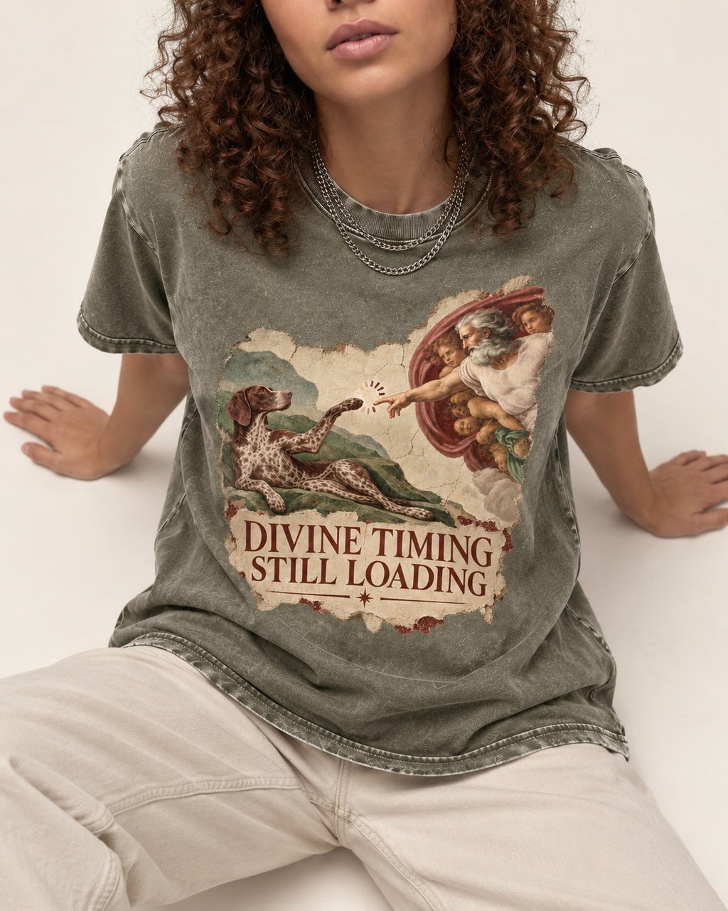 German Shorthaired Pointer Divine Timing Still Loading Creation Scene Graphic Washed Tee in Army Green, worn by a seated model