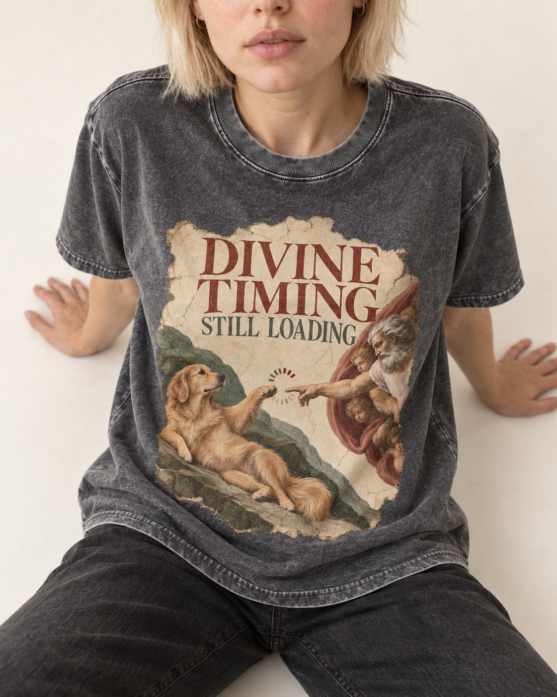 Divine Timing Still Loading Creation Scene Golden Retriever Graphic Washed Tee in Gray, worn by a seated model