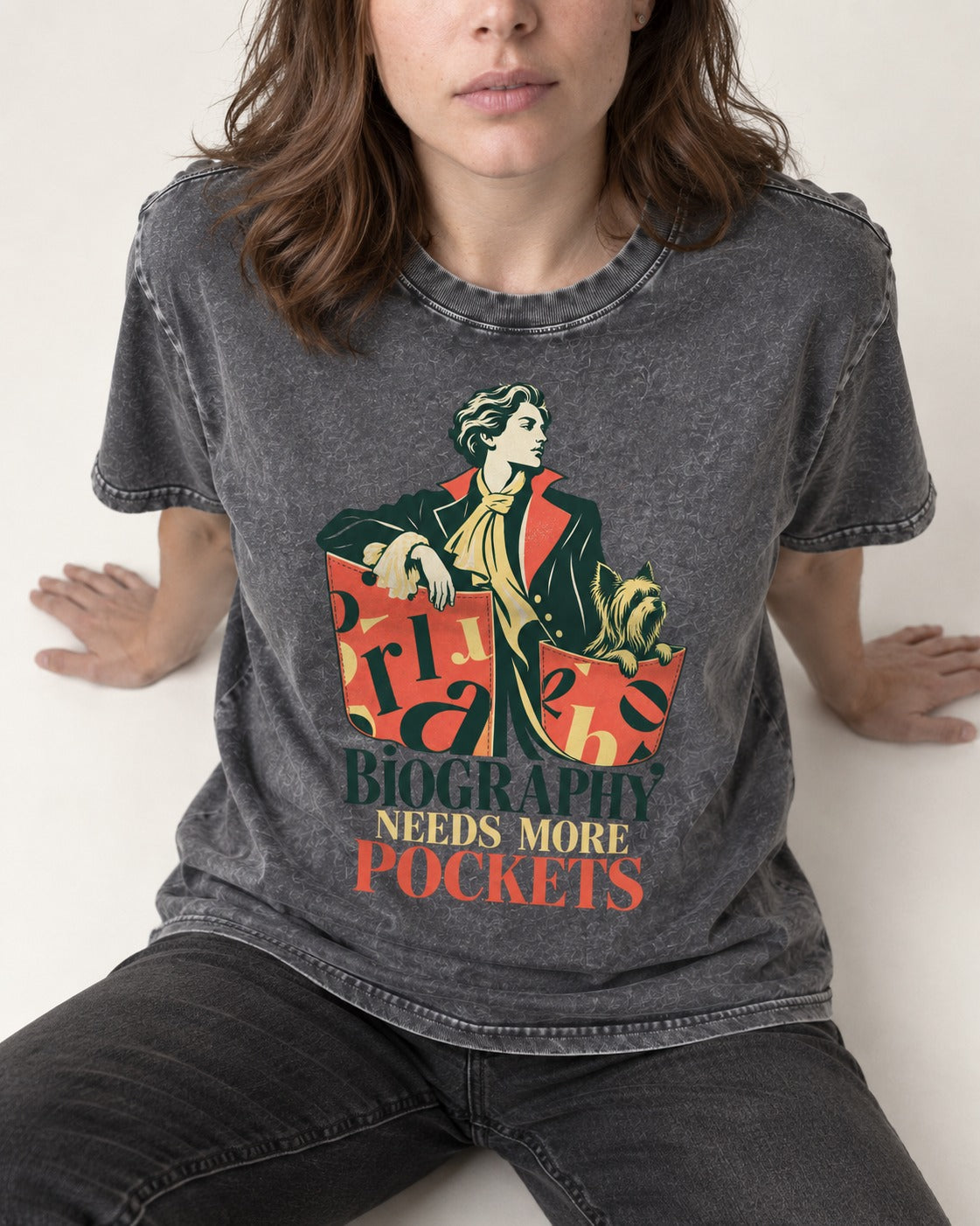 Yorkshire Terrier Biography Needs More Pockets Literary Portrait Graphic Washed Tee in Gray, worn by a seated model