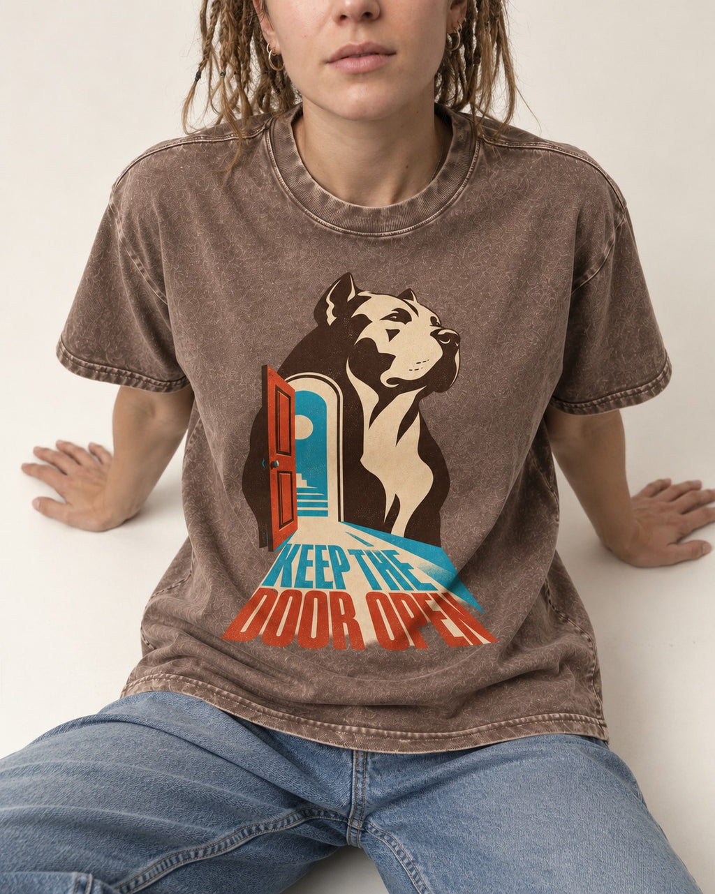 Keep the Door Open Pitbull Washed Tee in Coffee, worn by a seated model