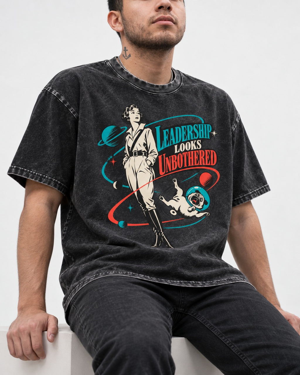 Pug Leadership Looks Unbothered Space Graphic Washed Tee in Black, worn by a seated model
