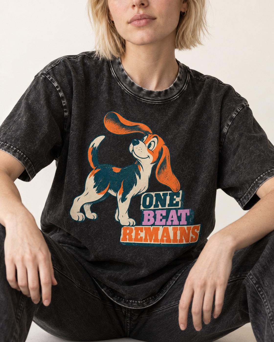 Retro Beagle One Beat Remains Washed Tee in Black, worn by a seated model