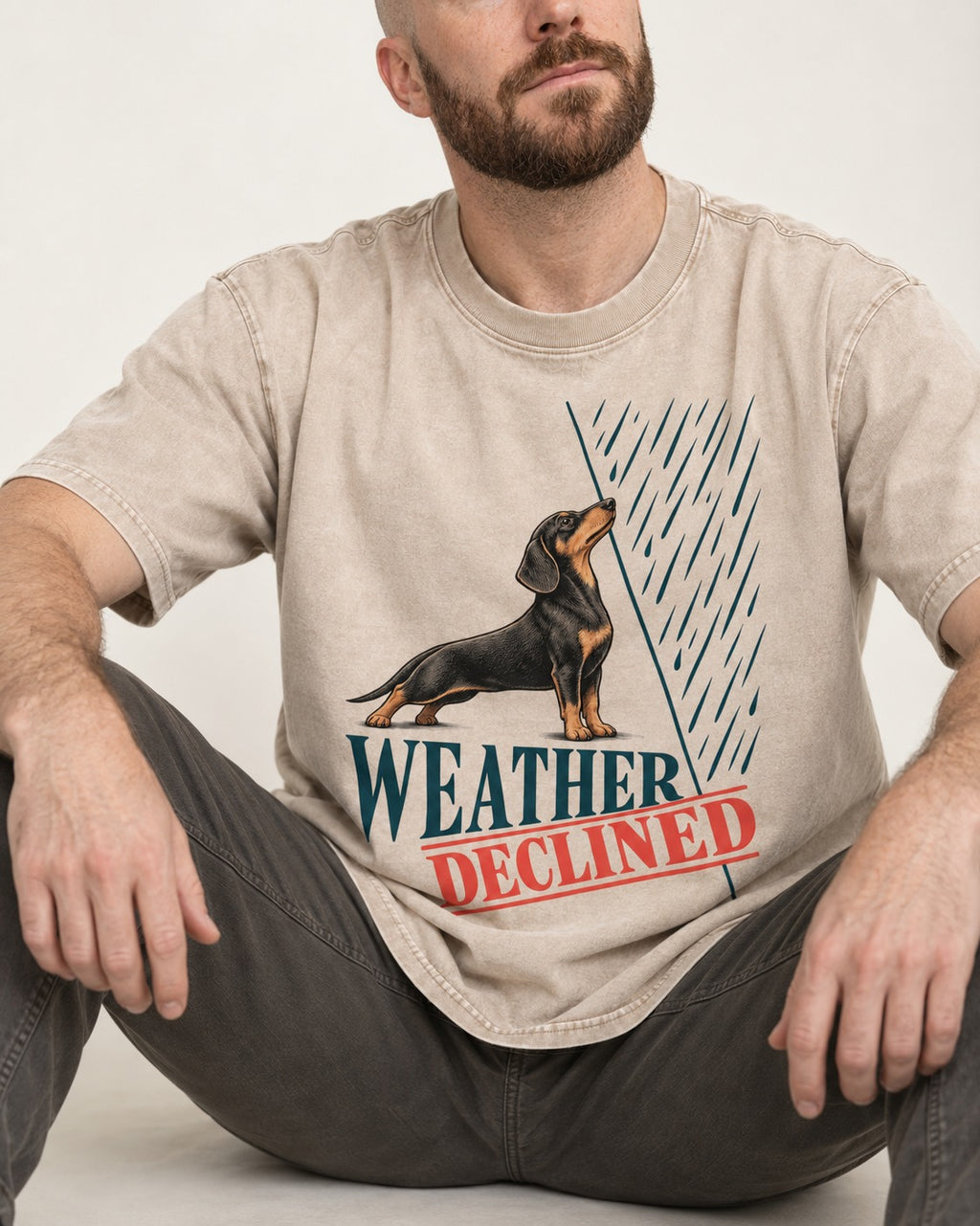 Weather Declined by Dachshund Washed Tee in Apricot, worn by a seated model