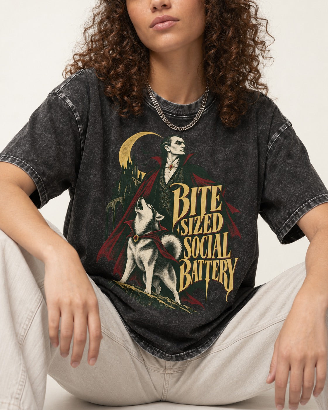 Husky Bite Sized Social Battery Vampire Graphic Washed Tee in Black, worn by a seated model