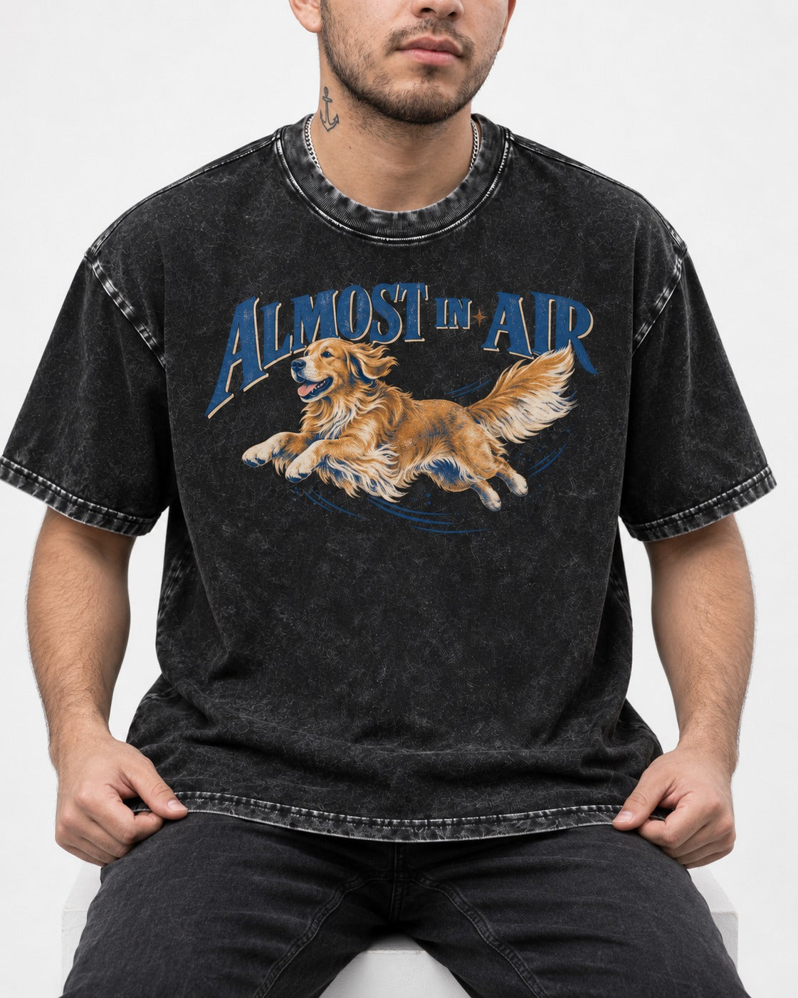 Golden Retriever Almost in Air Flying Graphic Washed Tee in Black, worn by a seated model
