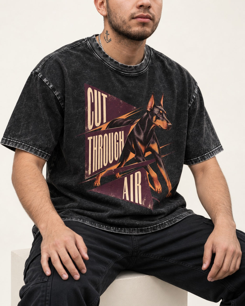 Doberman Cut Through Air Graphic Washed Tee in Black, worn by a seated model