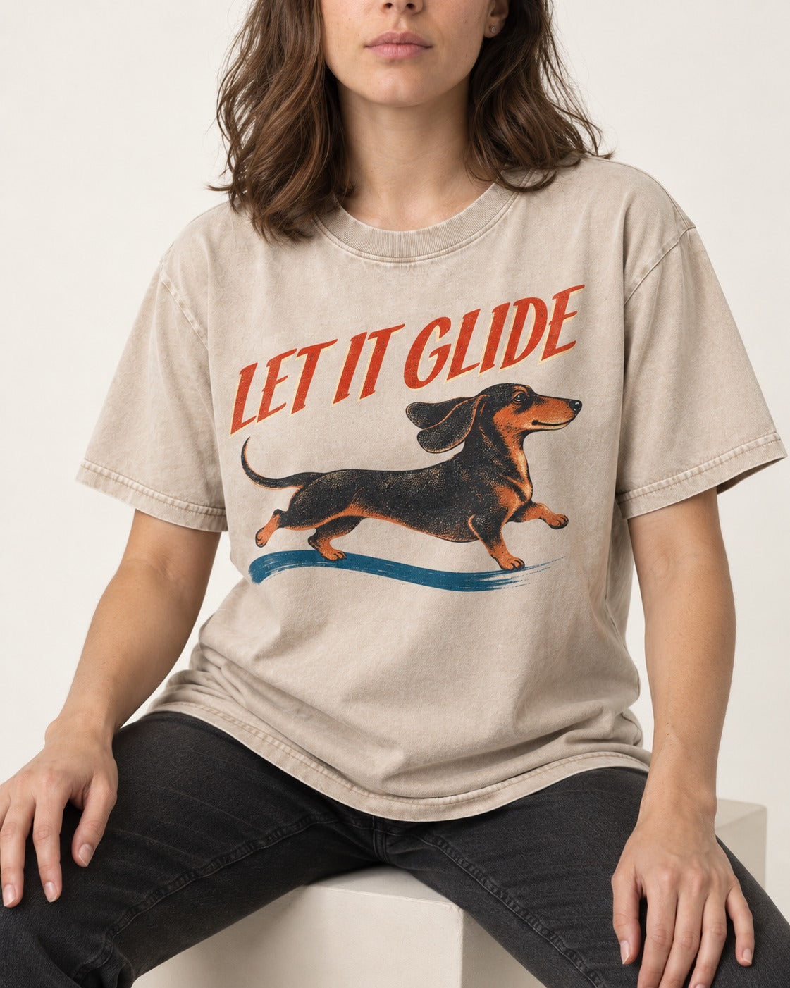 Let It Glide Dachshund Washed Tee in Apricot, worn by a seated model