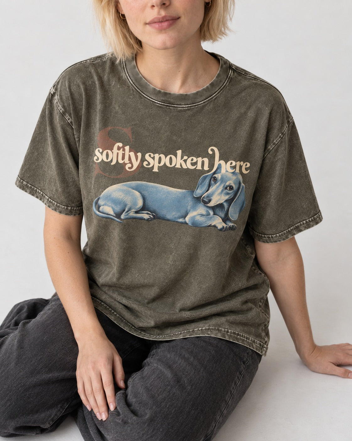 Dachshund Softly Spoken Here Reclining Portrait Graphic Washed Tee in Army Green, worn by a seated model