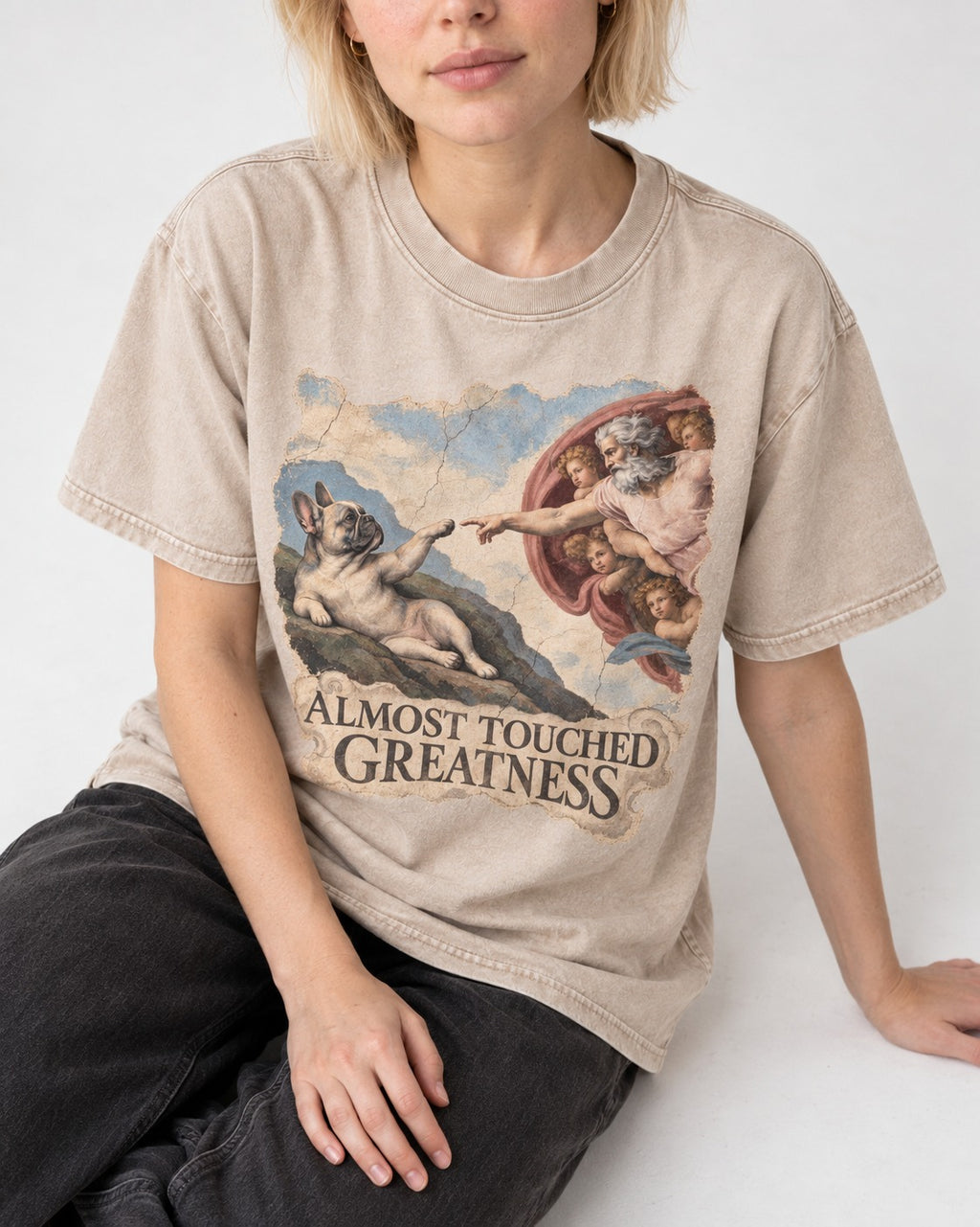 Frenchie Almost Touched Greatness Washed Tee in Apricot, worn by a seated model