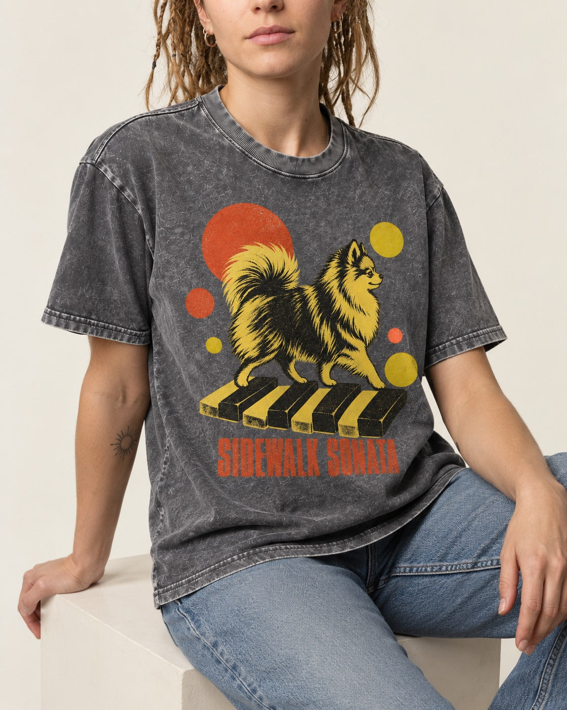 Pomeranian Sidewalk Sonata Piano Graphic Washed Tee in Gray, worn by a seated model