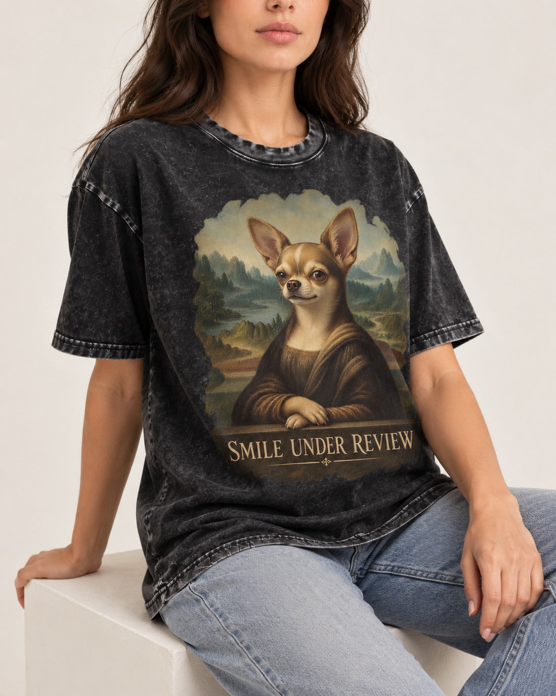 Chihuahua Smile Under Review Mona Lisa Portrait Washed Tee in Black, worn by a seated model