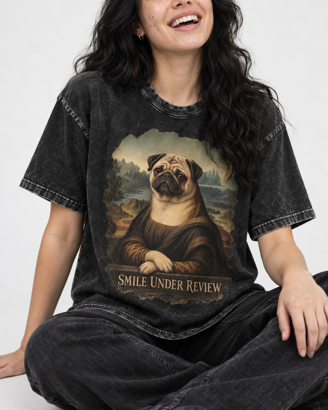 Pug Smile Under Review Mona Lisa Graphic Washed Tee in Black, worn by a seated model