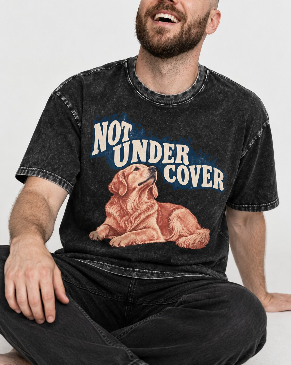 Not Under Cover Reclining Golden Retriever Graphic Washed Tee in Black, worn by a seated model