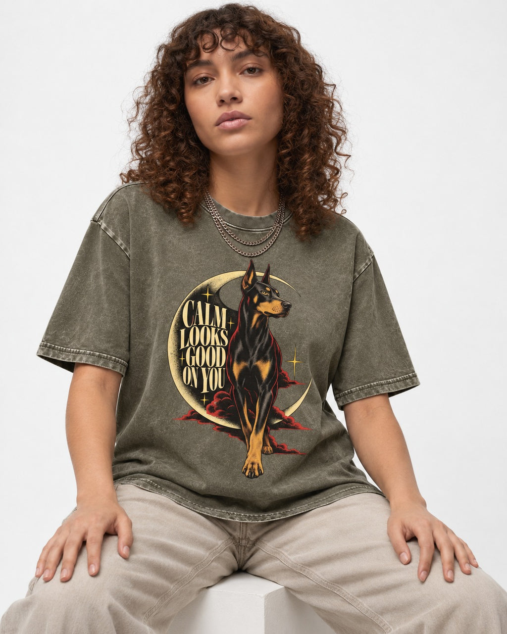 Doberman Calm Looks Good on You Crescent Graphic Washed Tee in Army Green, worn by a seated model