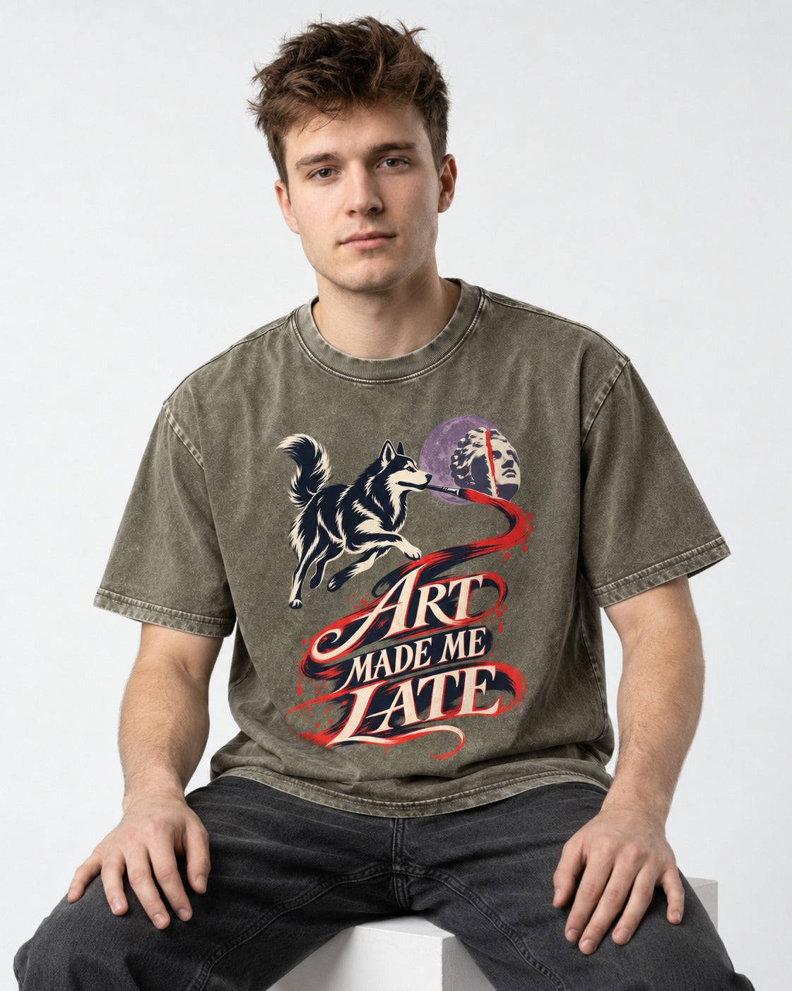 Husky Art Made Me Late Paintbrush Graphic Washed Tee in Army Green, worn by a seated model