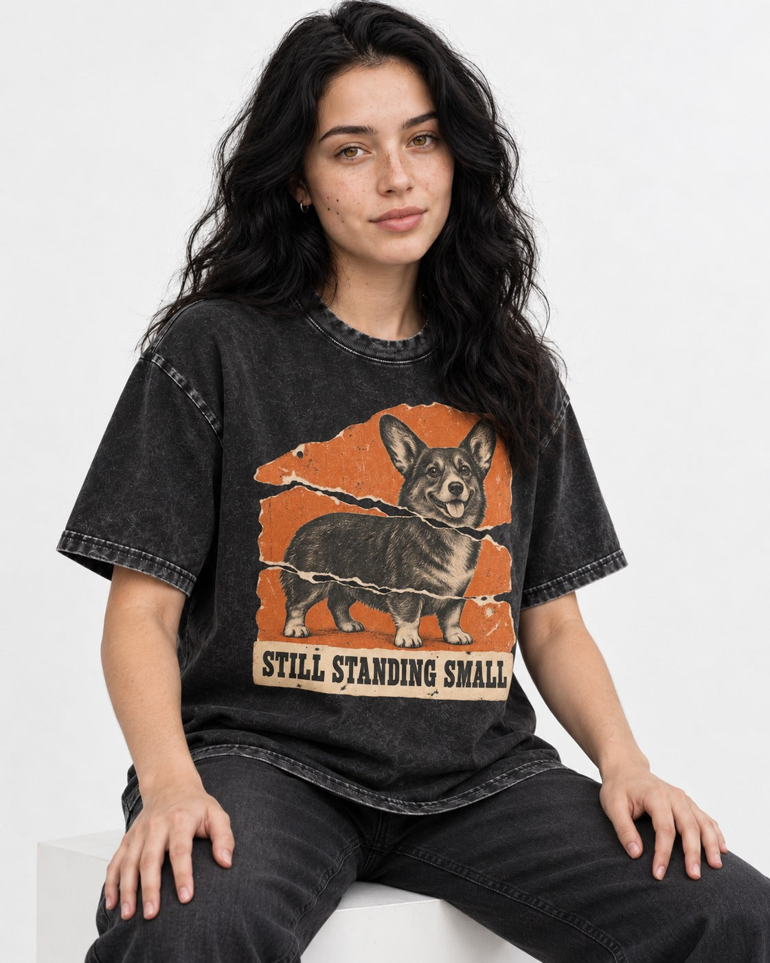Corgi Still Standing Small Torn Poster Washed Tee in Black, worn by a seated model