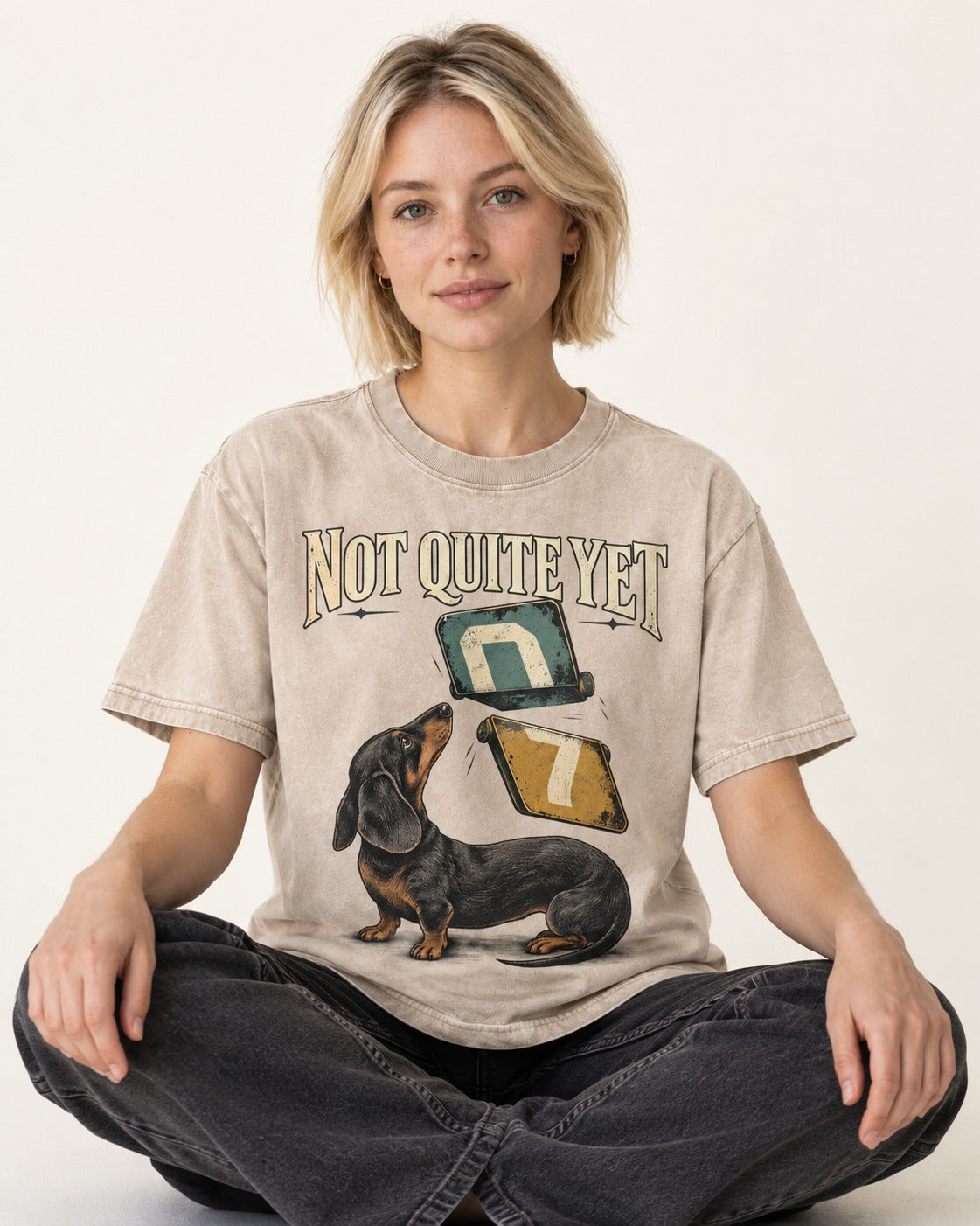 Not Quite Yet Dachshund Washed Tee in Apricot, worn by a seated model