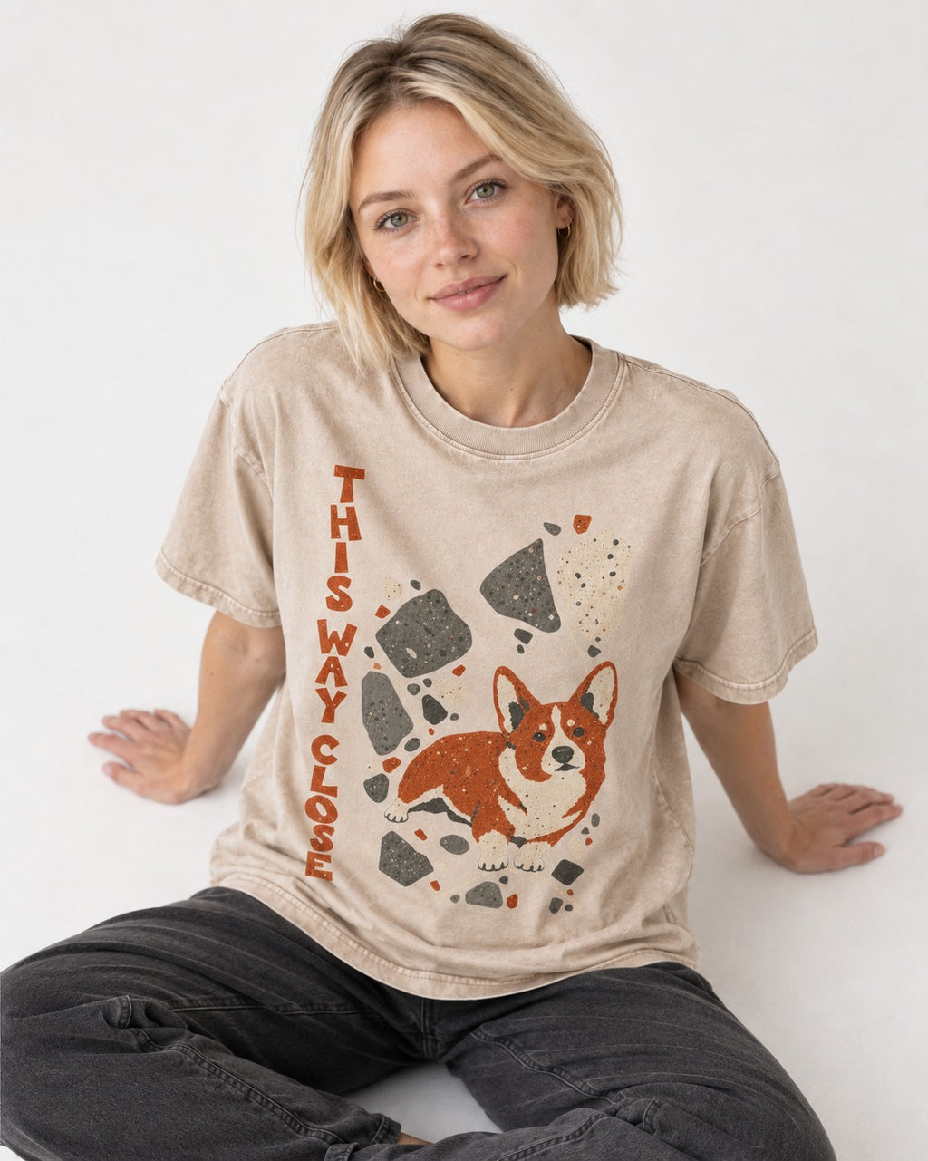 Corgi This Way Close Rubble Graphic Washed Tee in Apricot, worn by a seated model
