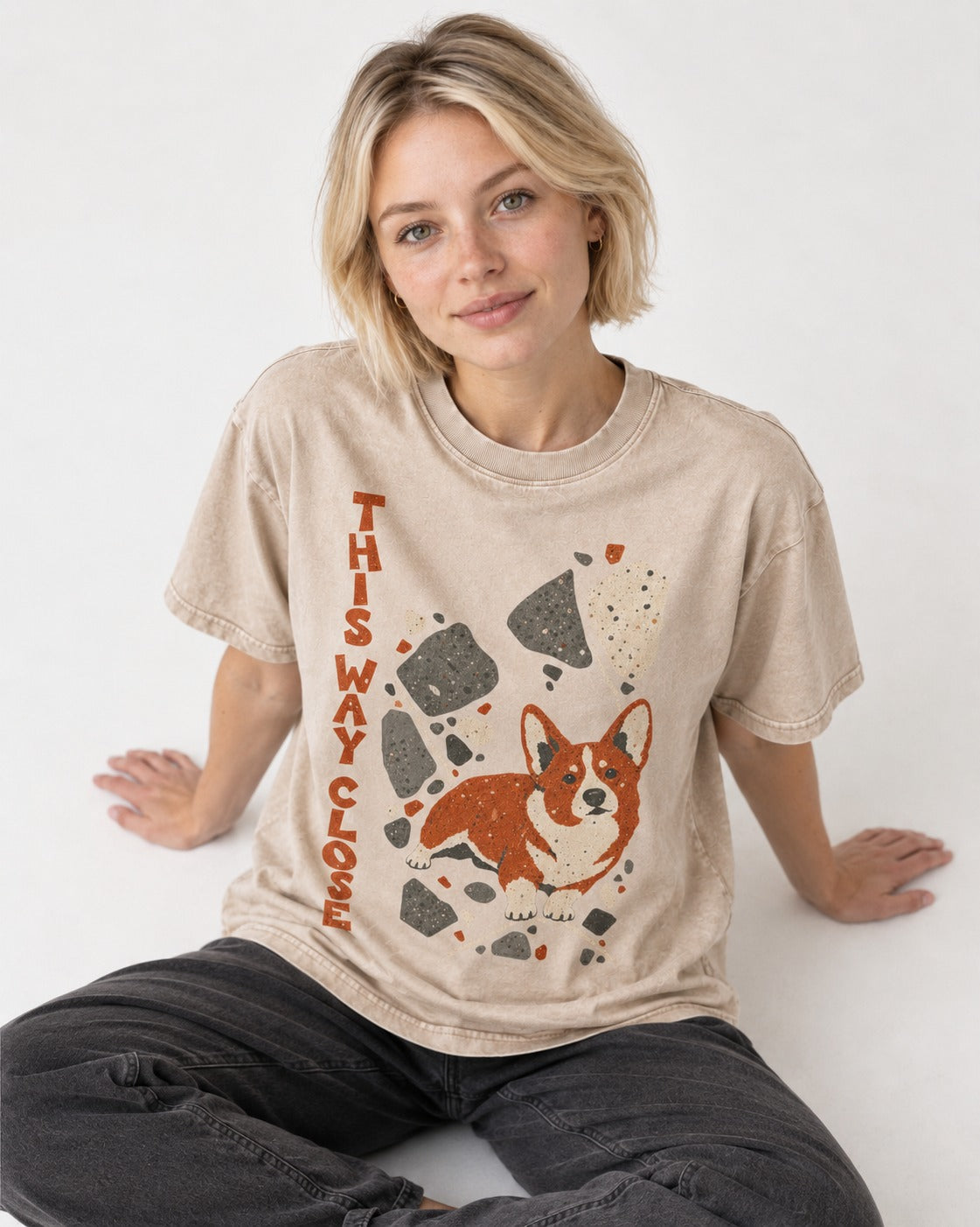 Corgi This Way Close Rubble Graphic Washed Tee in Apricot, worn by a seated model