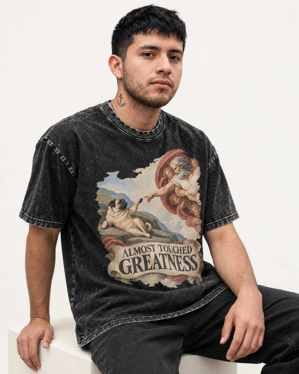 Pug Almost Touched Greatness Creation Parody Graphic Washed Tee in Black, worn by a seated model