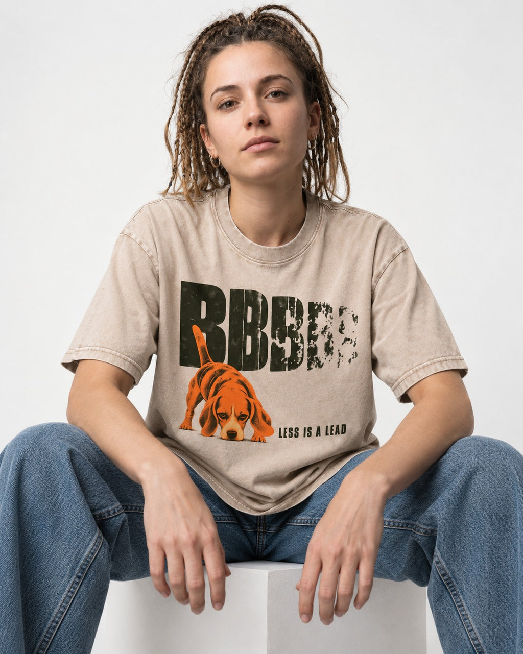 Less Is a Lead Beagle Washed Tee in Apricot, worn by a seated model