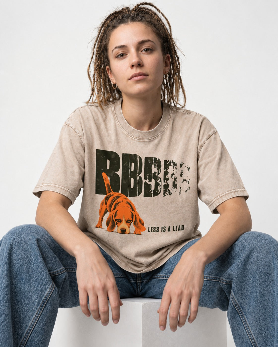 Less Is a Lead Beagle Washed Tee in Apricot, worn by a seated model