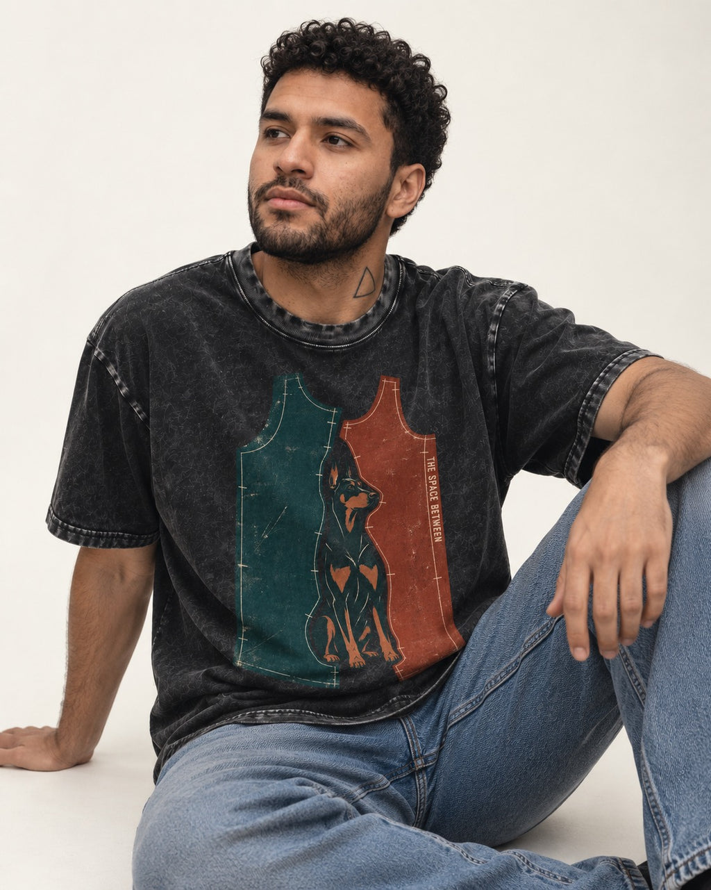 Doberman The Space Between Pattern Pieces Graphic Washed Tee in Black, worn by a seated model