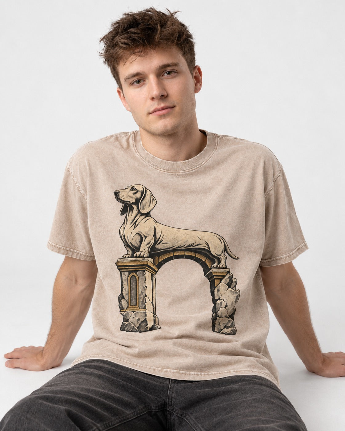 Dachshund Ruined Stone Arch Monument Graphic Washed Tee in Apricot, worn by a seated model