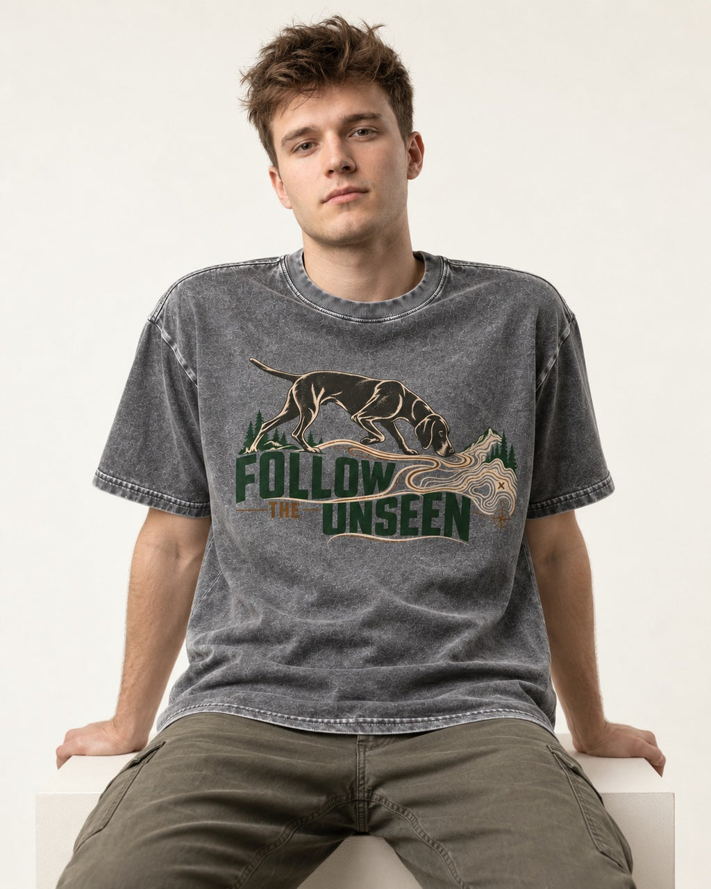 Follow the Unseen German Shorthaired Pointer Washed Tee in Gray, worn by a seated model
