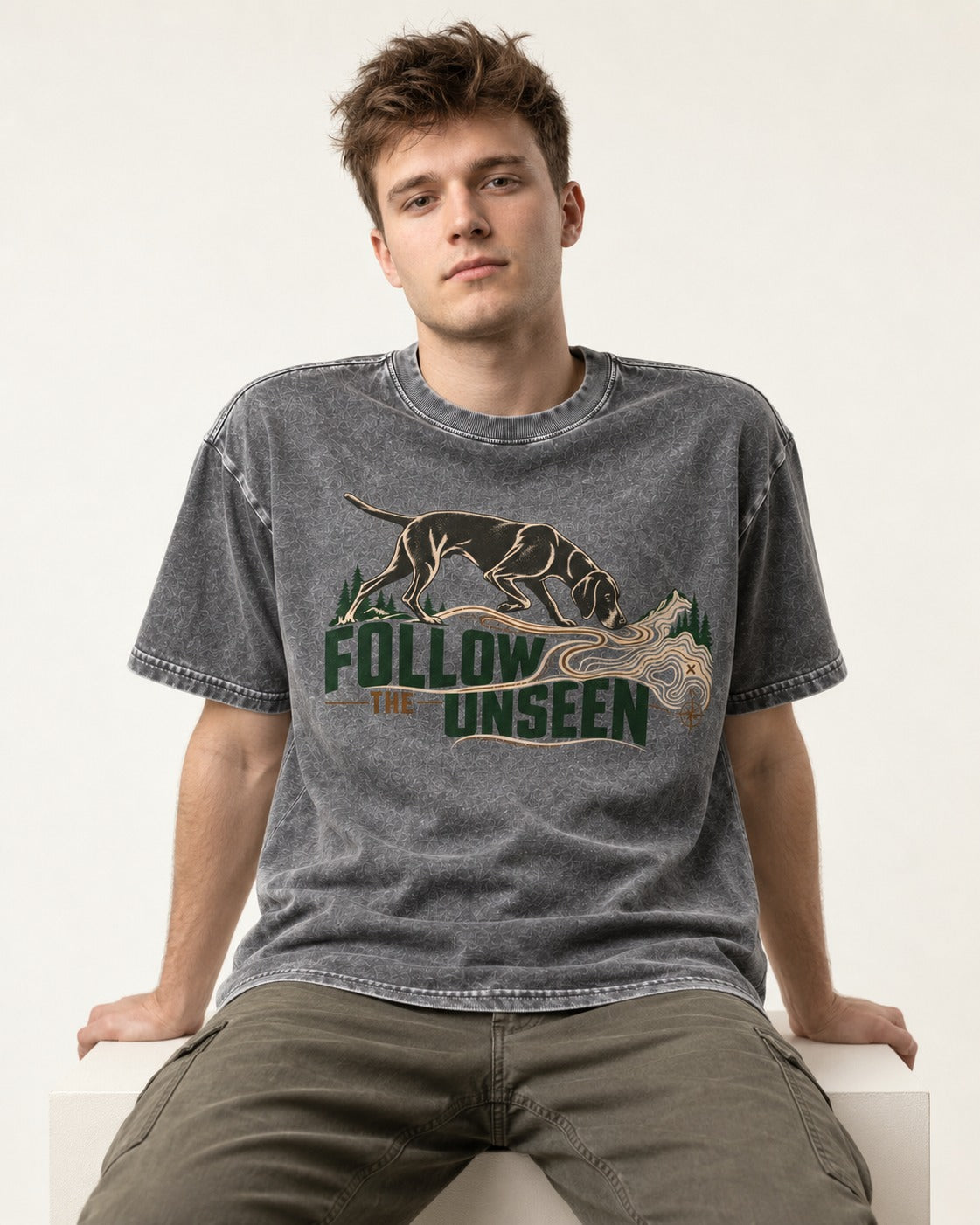 Follow the Unseen German Shorthaired Pointer Washed Tee in Gray, worn by a seated model