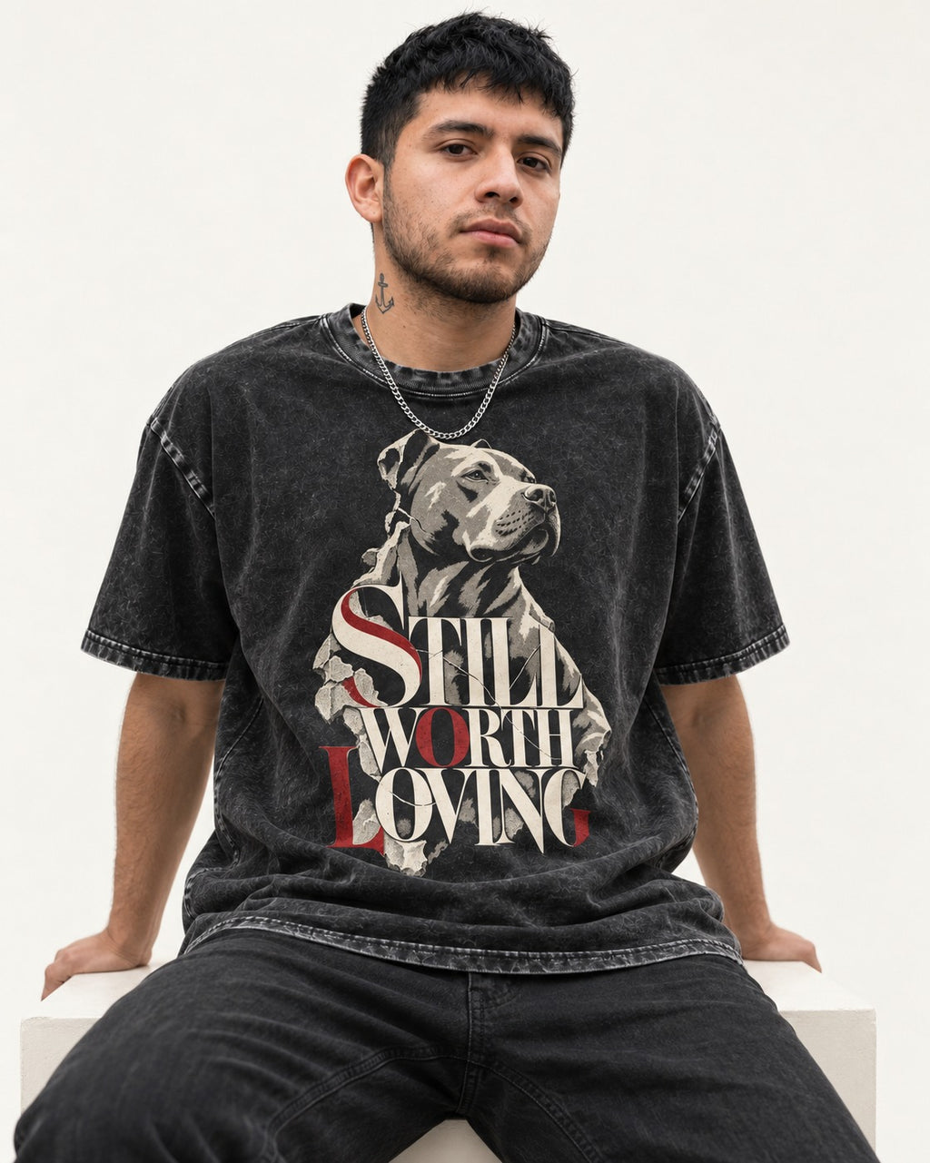 Pitbull Still Worth Loving Torn Poster Portrait Graphic Washed Tee in Black, worn by a seated model