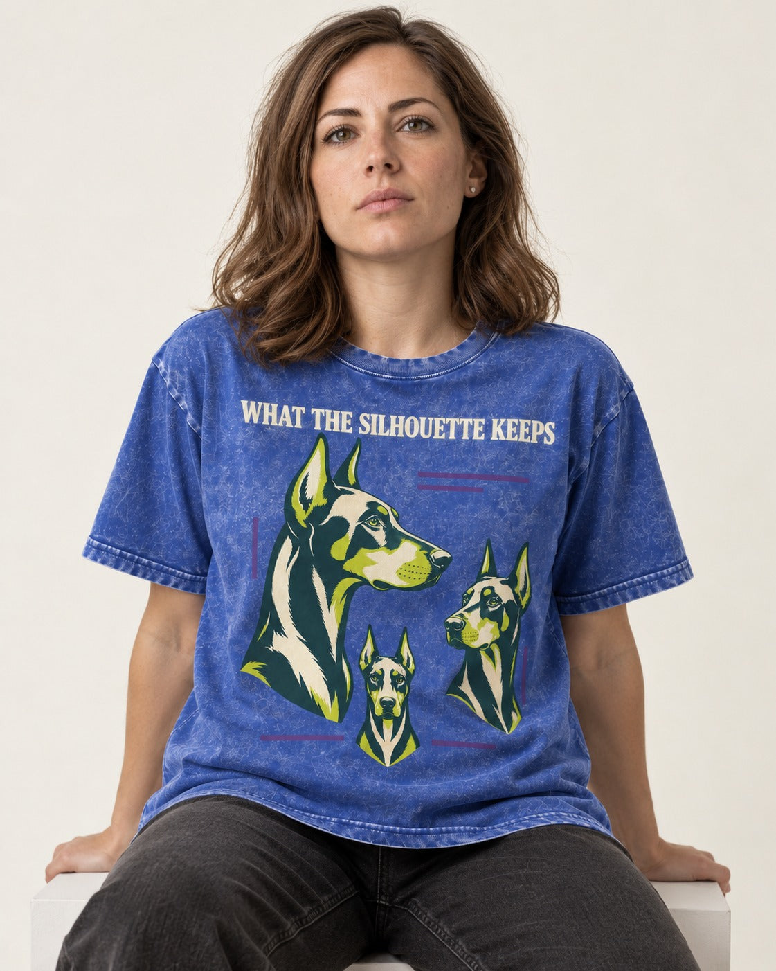 Doberman What the Silhouette Keeps Three Portrait Graphic Washed Tee in Royal Blue, worn by a seated model