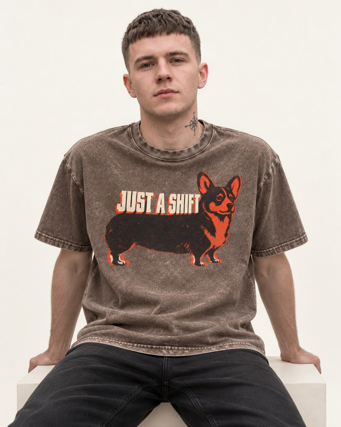 Corgi Just a Shift Typographic Graphic Washed Tee in Coffee, worn by a seated model