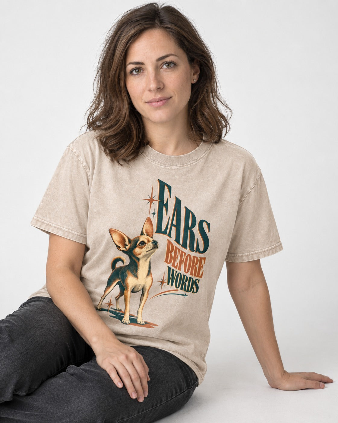 Chihuahua Ears Before Words Retro Typography Washed Tee in Apricot, worn by a seated model