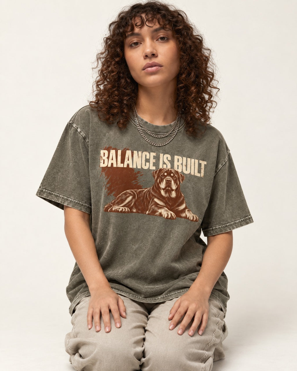 Rottweiler Balance Is Built Resting Strength Graphic Washed Tee in Army Green, worn by a seated model