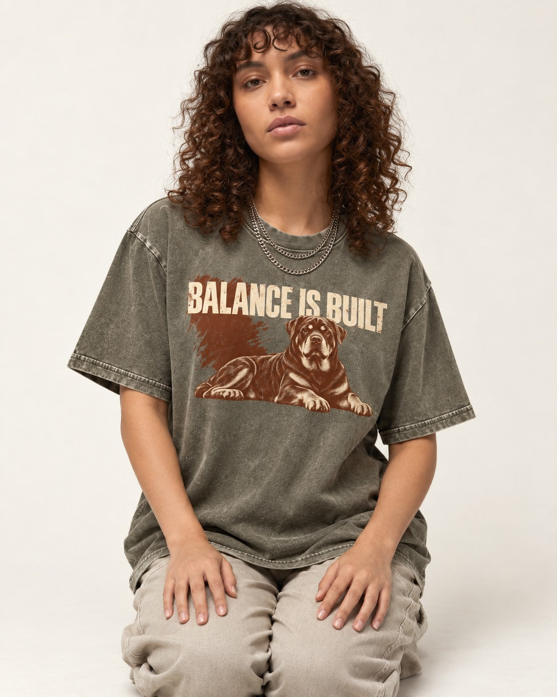 Rottweiler Balance Is Built Resting Strength Graphic Washed Tee in Army Green, worn by a seated model