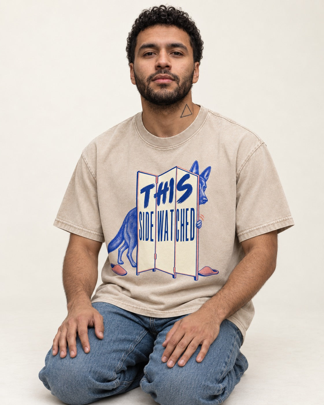 This Side Watched by German Shepherd Dog Washed Tee in Apricot, worn by a seated model