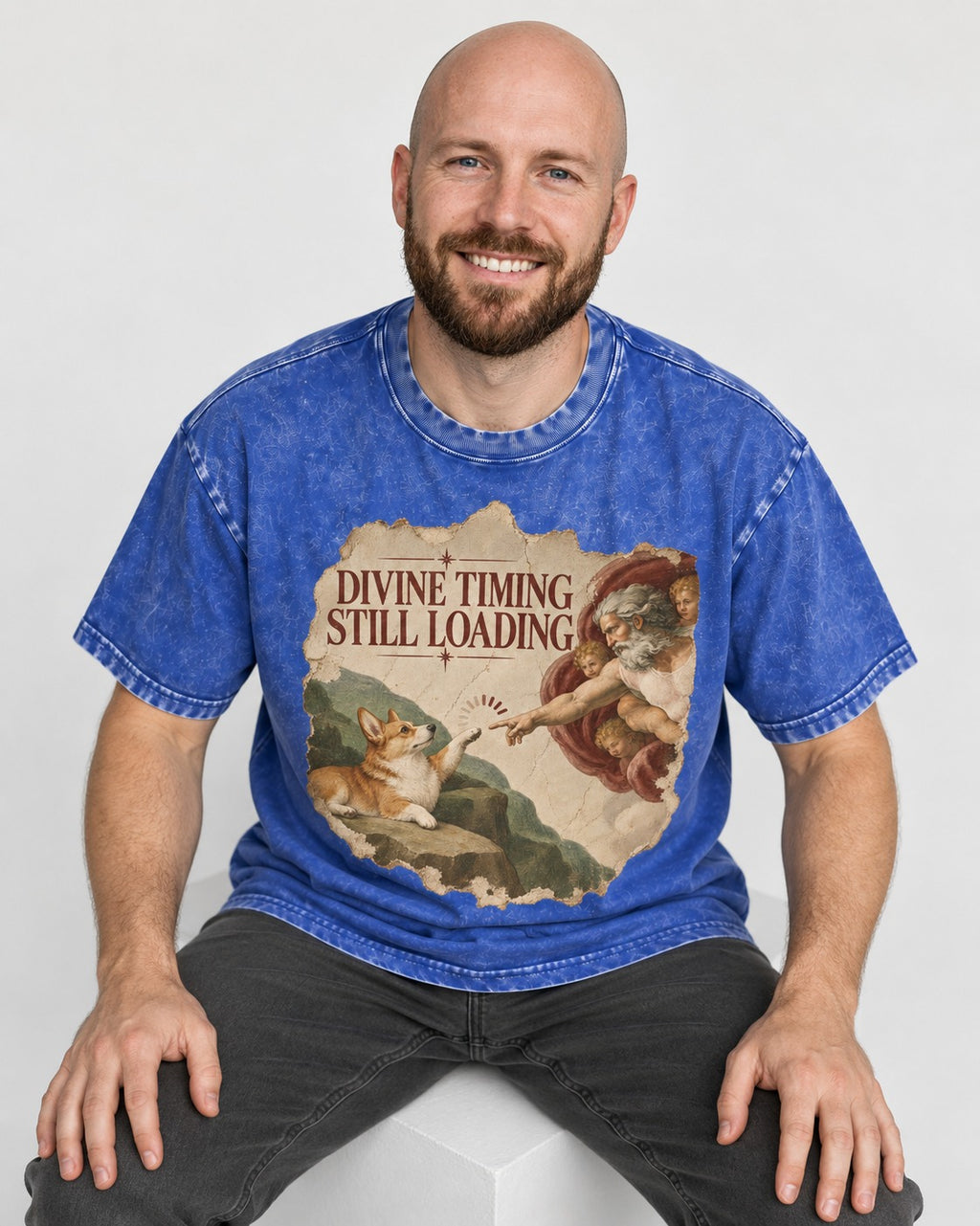 Corgi Divine Timing Still Loading Creation Parody Washed Tee in Royal Blue, worn by a seated model